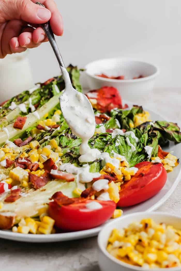 This smoky Grilled Romaine Salad is simple and summery, with tomatoes, sweet corn, crispy bacon and homemade buttermilk ranch dressing. Yum! Drizzling grilled romaine salad with buttermilk ranch dressing