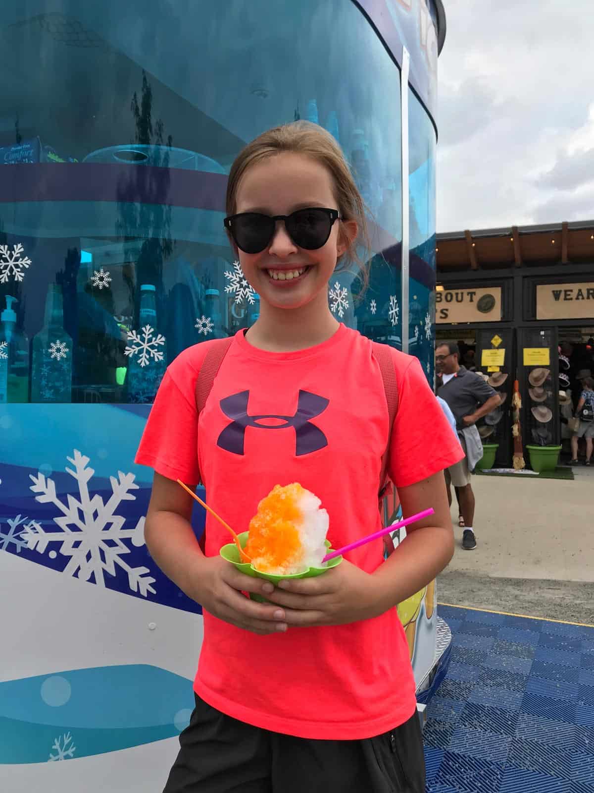 girl with sunglasses on, holding a cup of shave ice