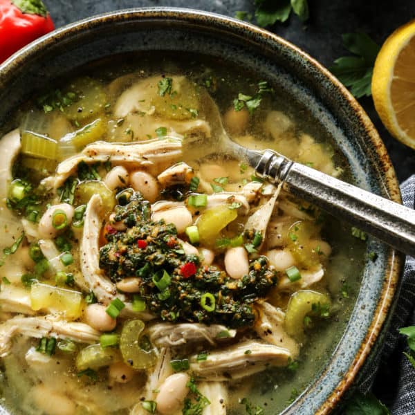 Chicken Chimichurri Soup with White Beans in a pottery bowl with spoon