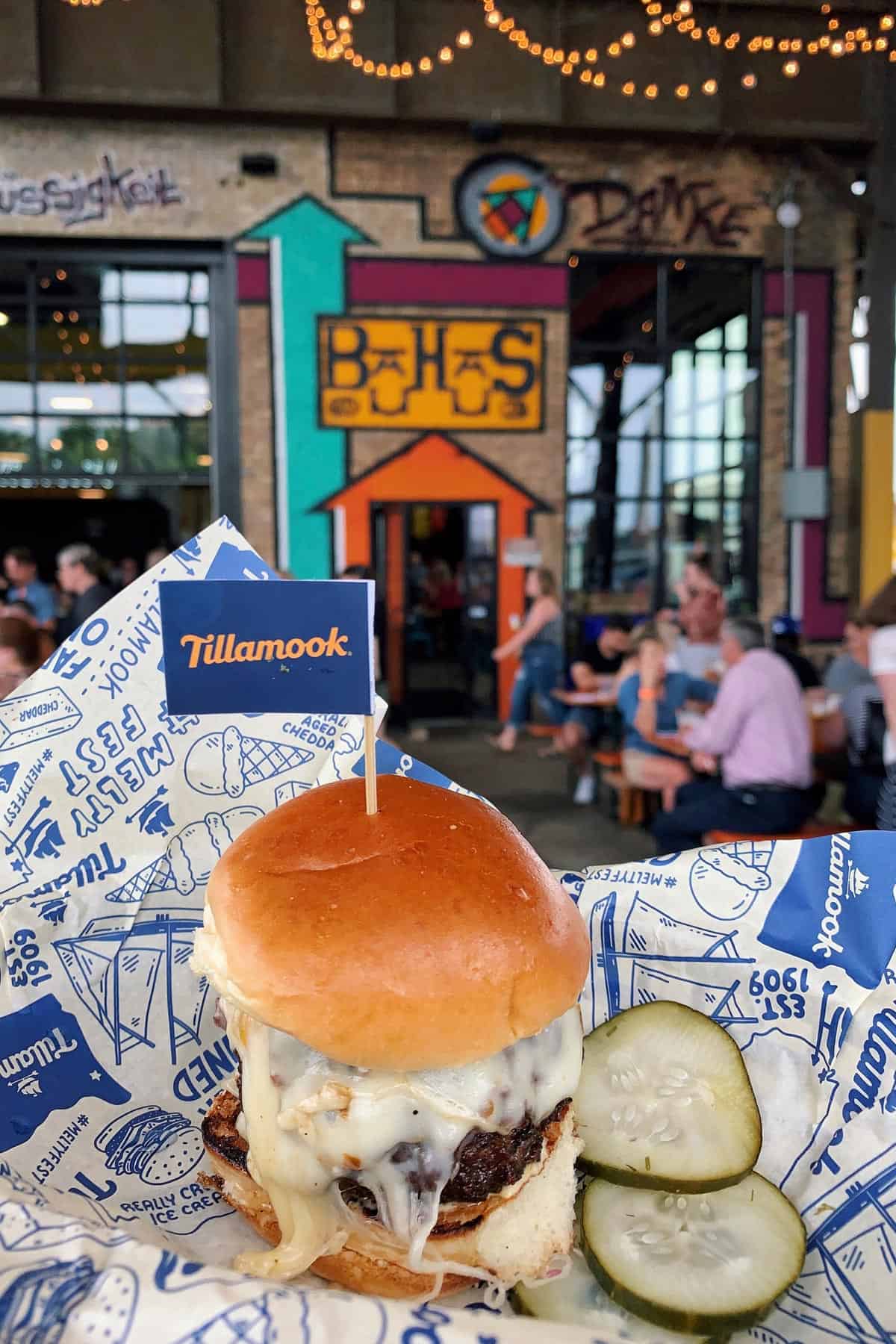 a slider sized burger with melted pepper jack cheese and a side of pickles