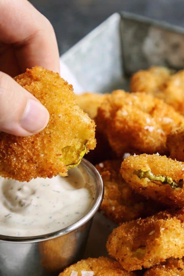 dipping a fried pickle chip into ranch dip