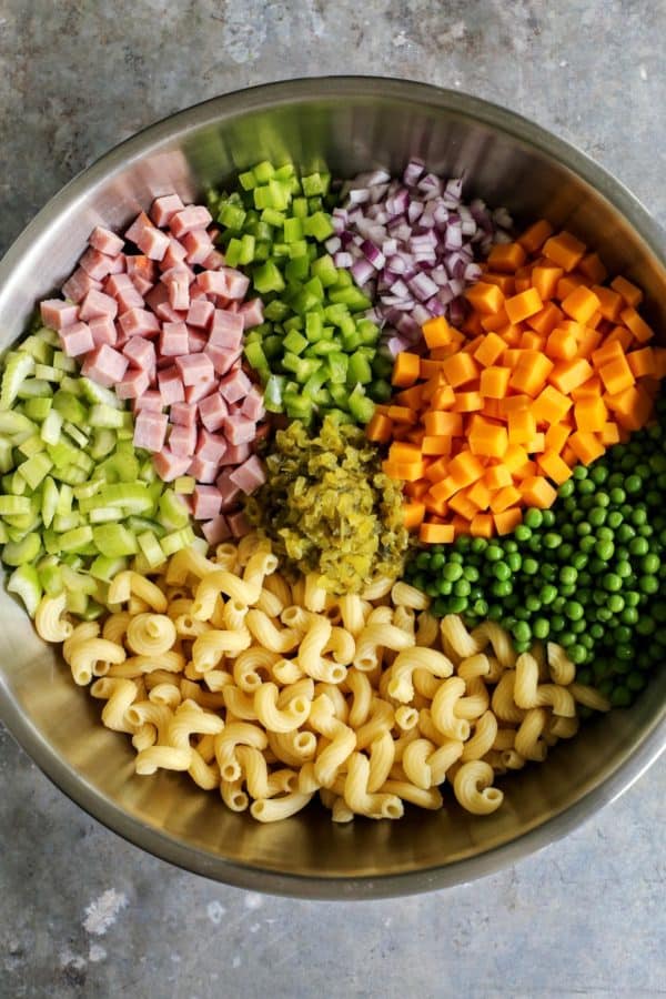 ingredients for macaroni salad - macaroni, celery, ham, green pepper, red onion, cheese, peas, pickle relish