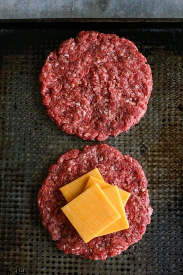 a sheet pan with hamburger patties and slices of cheese
