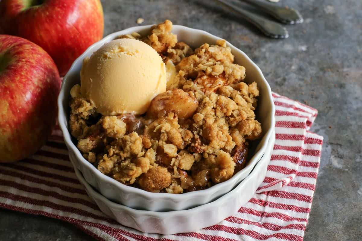 Apple crisp in a white ramekin with a scoop of ice cream