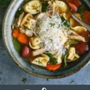 pinterest image of turkey tortellini soup in blue pottery bowl, with fresh Parmesan and herbs