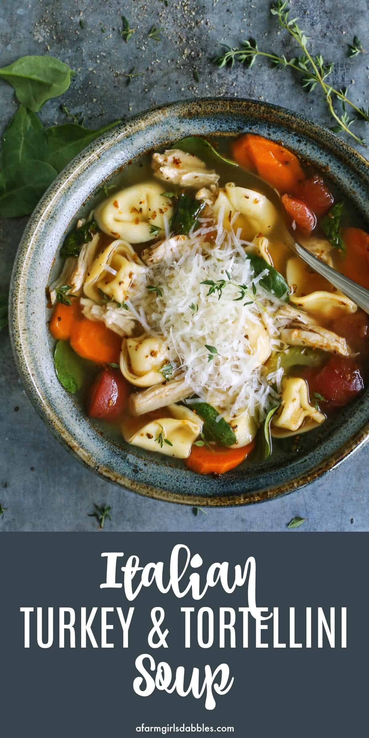 pinterest image of turkey tortellini soup in blue pottery bowl, with fresh Parmesan and herbs