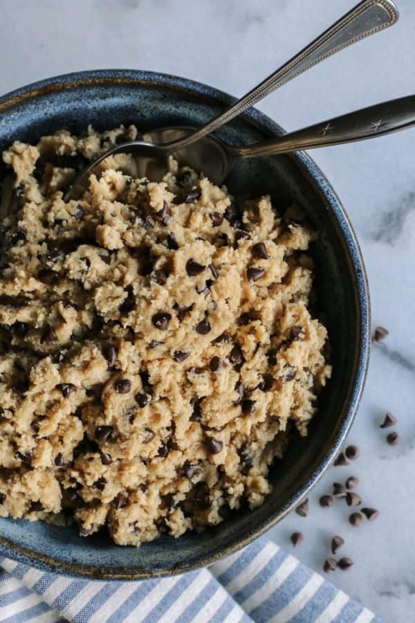 a big bowl of cookie dough with 2 spoons in it