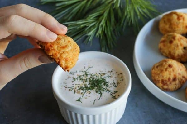 dipping a baked olive cheese ball into buttermilk ranch dip
