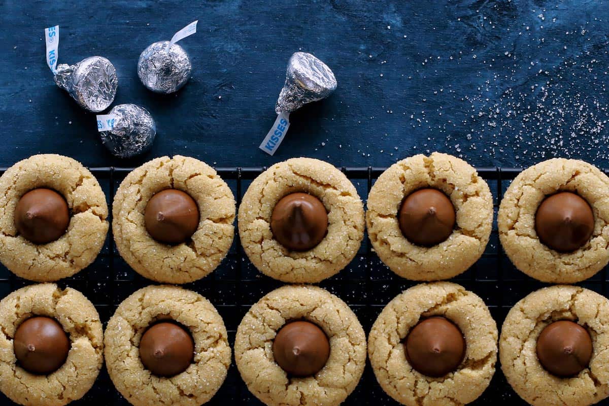 peanut butter blossoms on a cooling rack and Hershey's Kisses