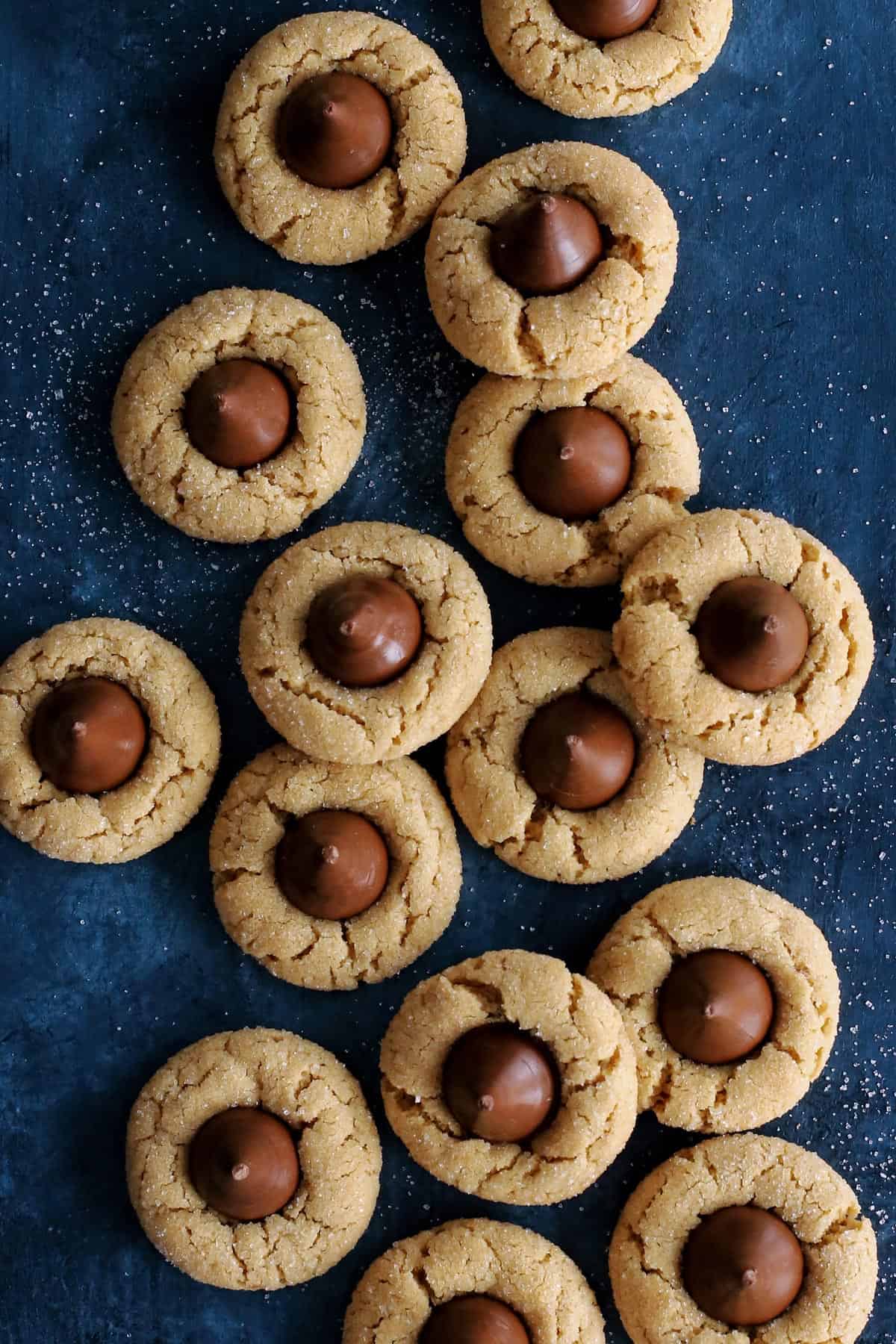 peanut butter cookies with a Hershey's Kiss laid out on a dark blue countertop