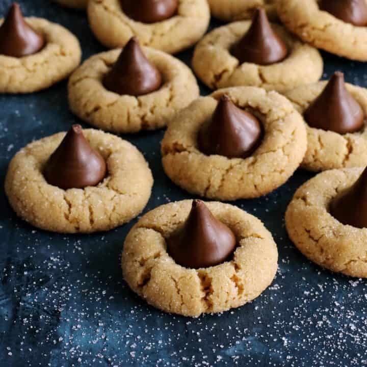 peanut butter cookies with a Hershey's Kiss laid out on a dark blue countertop