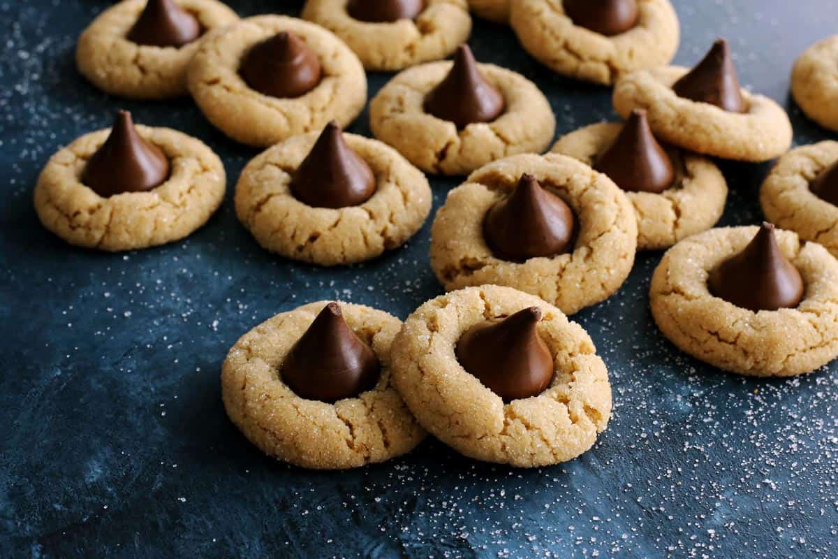 peanut butter blossom cookies laid out on a dark blue countertop