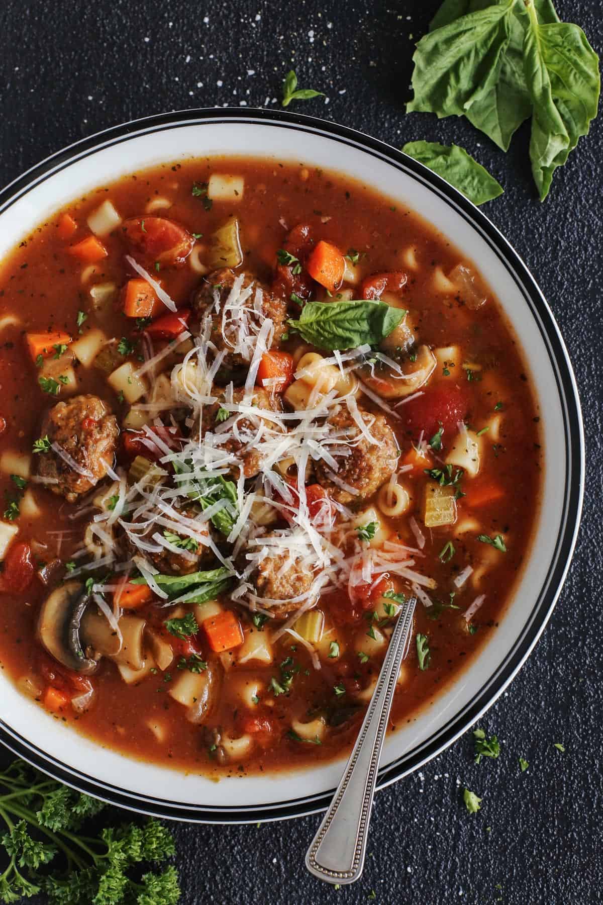 Italian Meatball Soup with tender homemade meatballs, vegetables and ditalini pasta. An easy dinner idea full of the flavors of Italy! meatball soup in a white bowl, with fresh basil