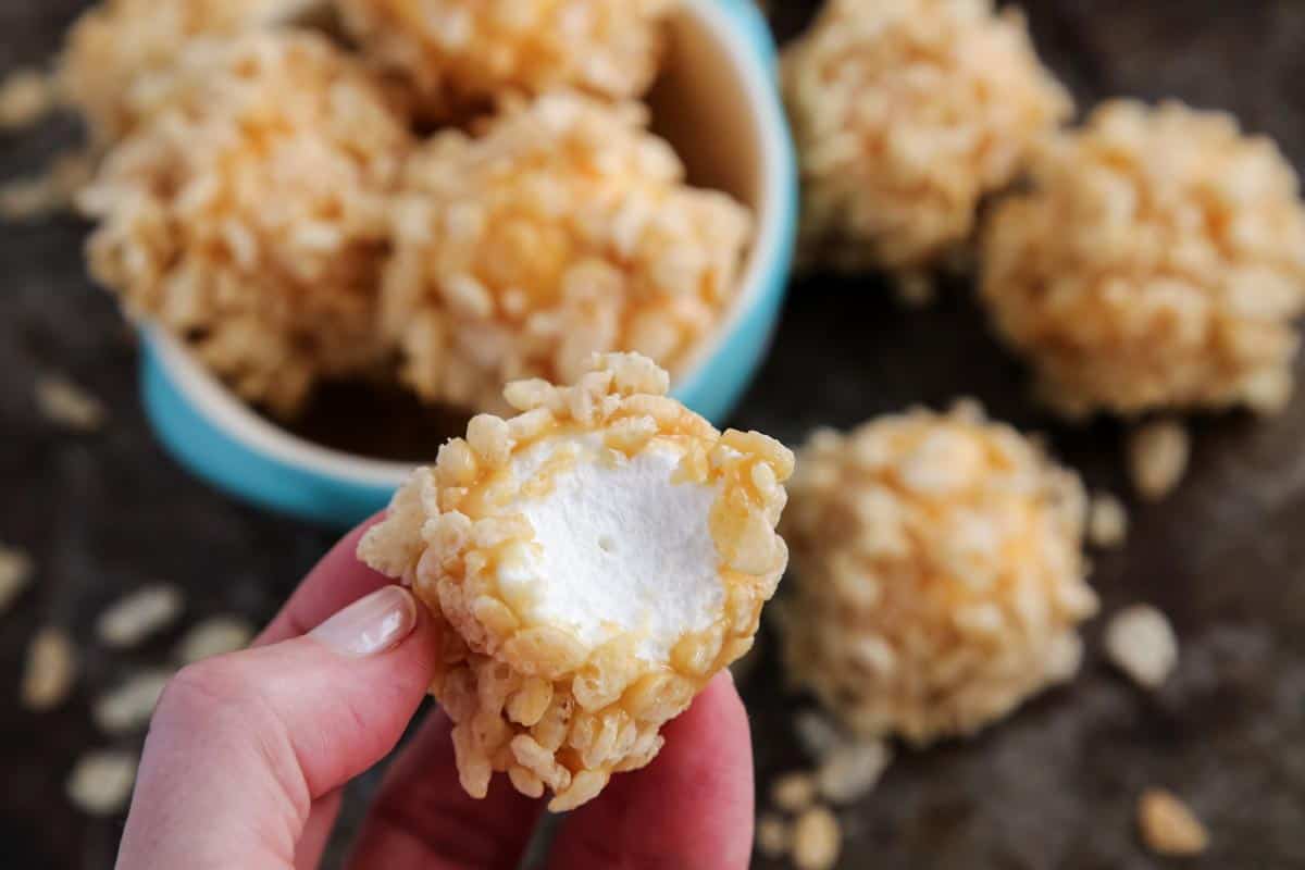 a marshmallow dipped in caramel and  coated with crispy rice cereal, bitten in half