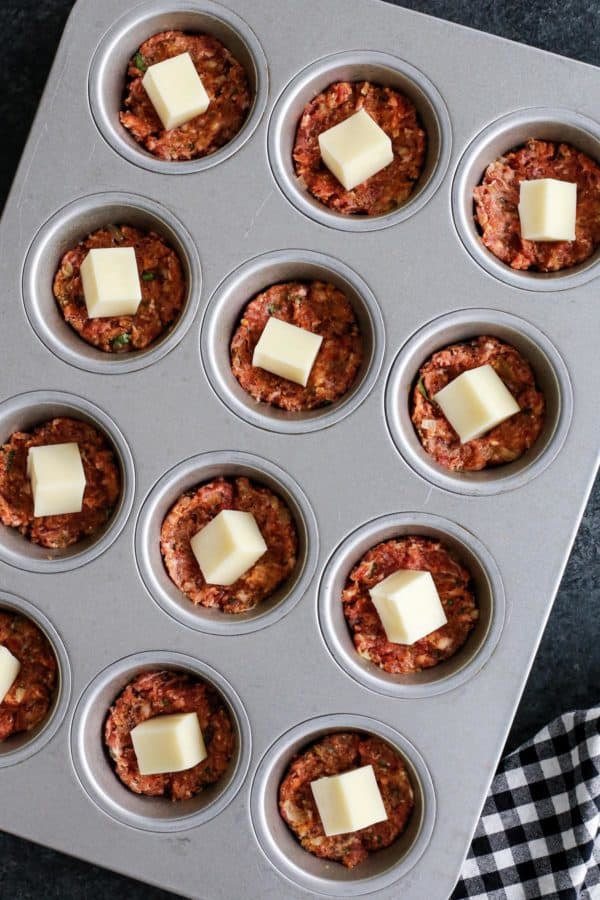 Meatloaf mixture and mozzarella cheese in muffin tin