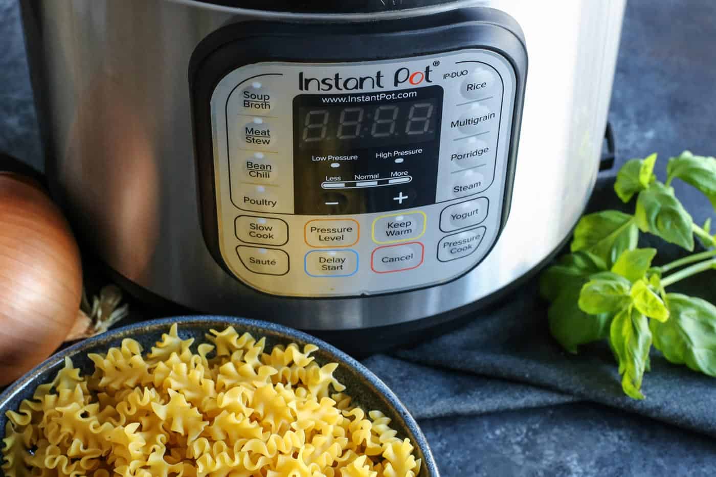 An instant pot next to a bowl of malfalda noodles