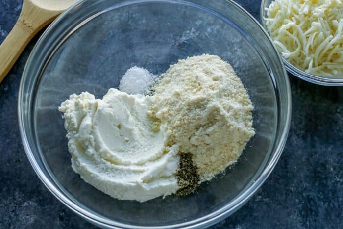 A bowl filled with ricotta, grated parmesan and salt and pepper