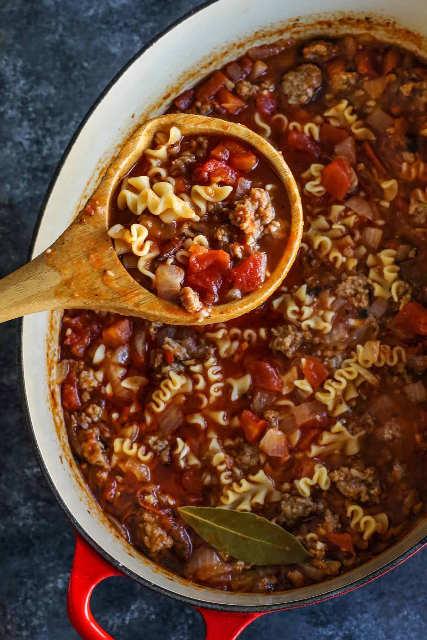 A wooden spoon filled with lasagna soup