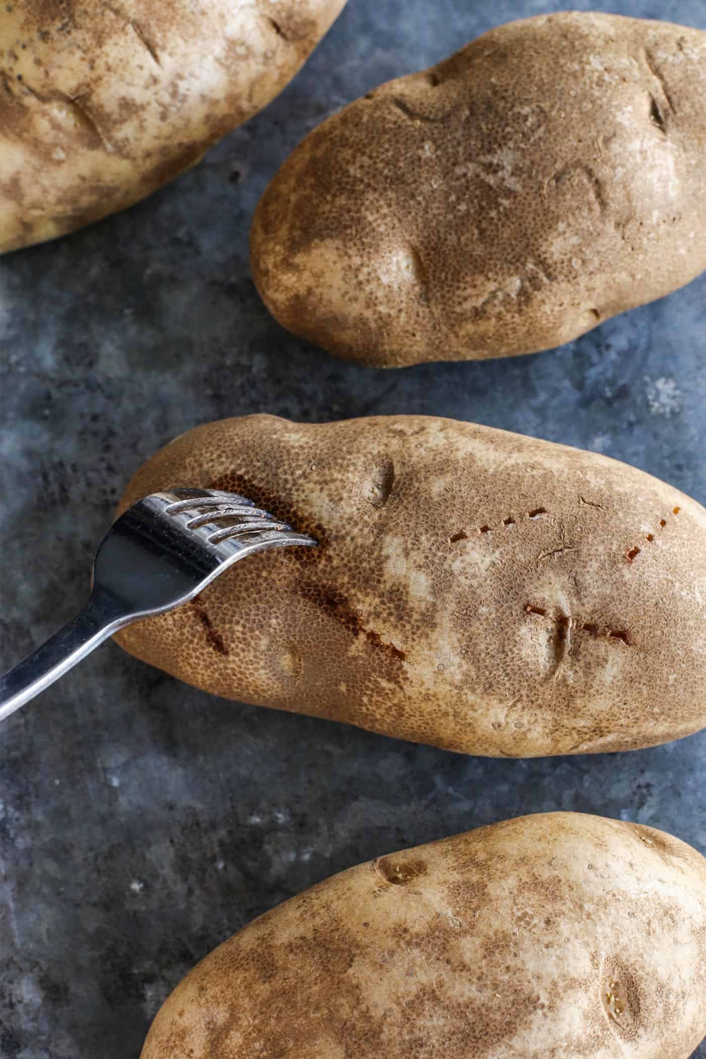 a fork poking Russet potatoes