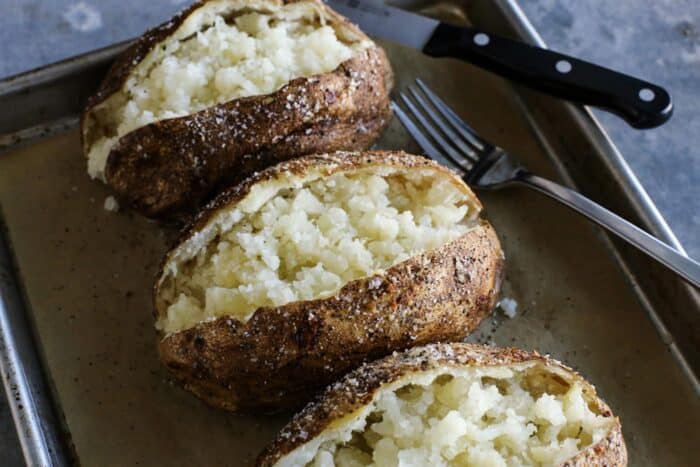 oven baked potatoes cut open on a pan