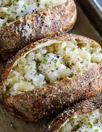 potatoes baked in the oven, split open, and topped with butter and chives