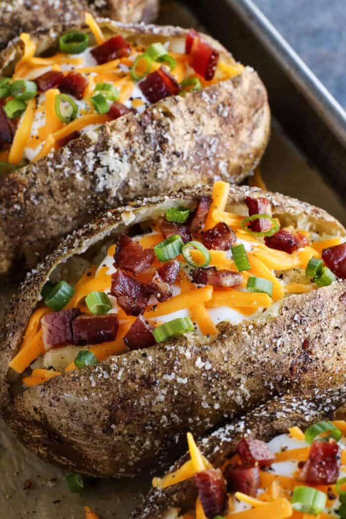 baked potatoes split open and topped with cheese and bacon