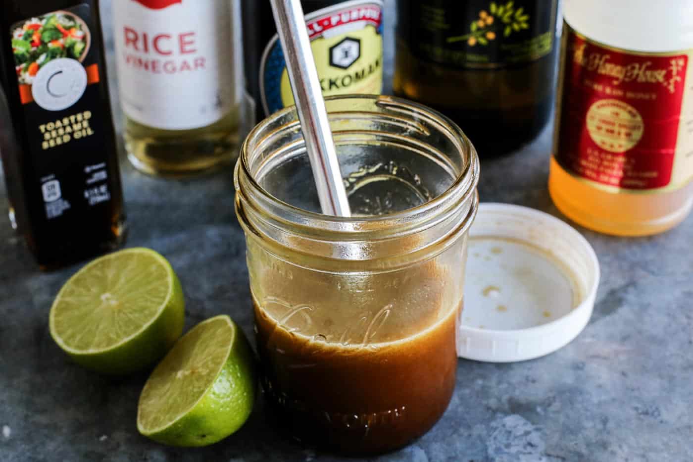 A mason jar with homemade vinaigrette next to a sliced lime.