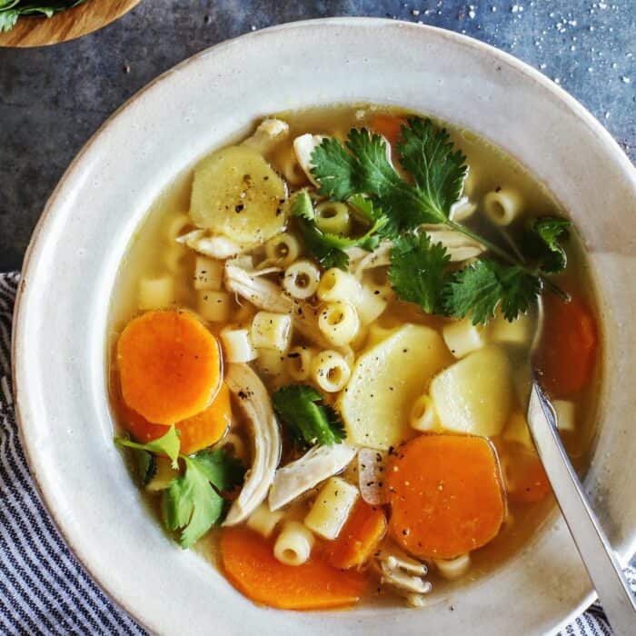 white bowl filled with chicken noodle soup with ginger and sweet potatoes