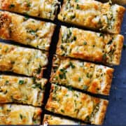pinterest image of cheesy garlic bread, cut into pieces
