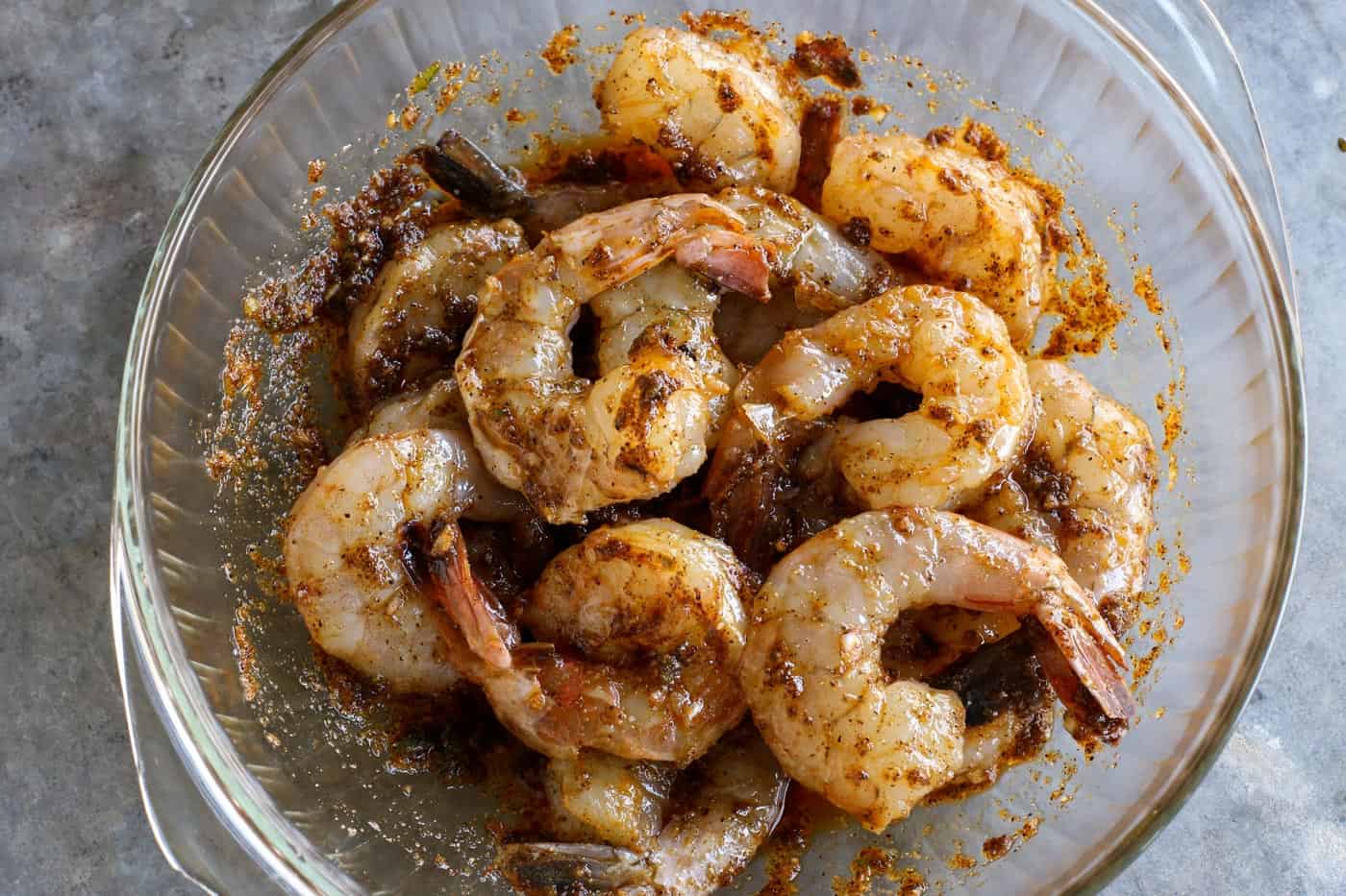 Shrimp with marinade in a glass bowl.