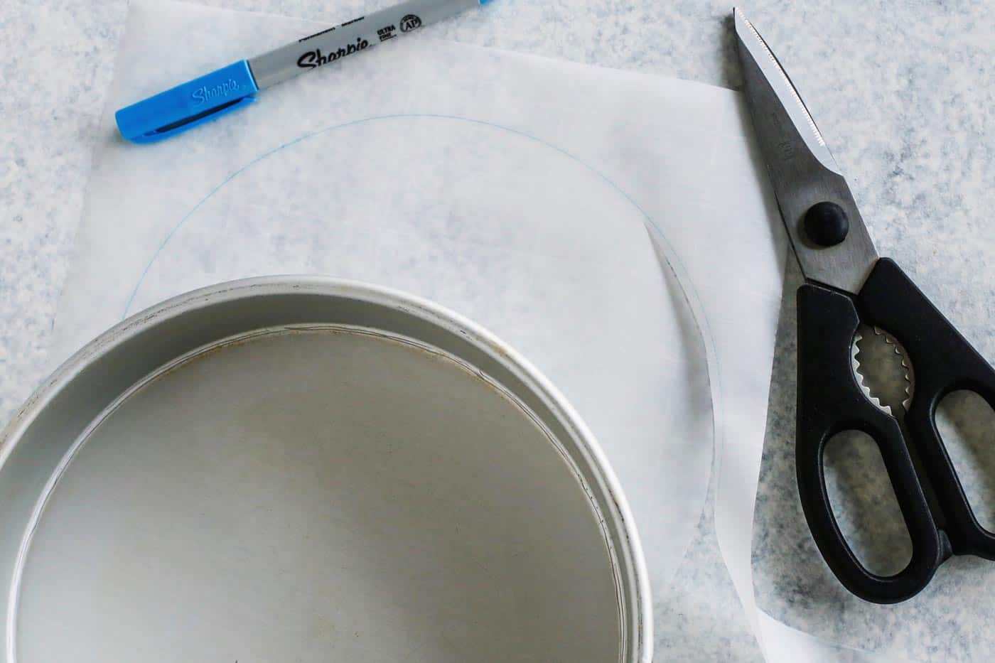 how to line a round cake pan with parchment paper, a marker, and a scissors