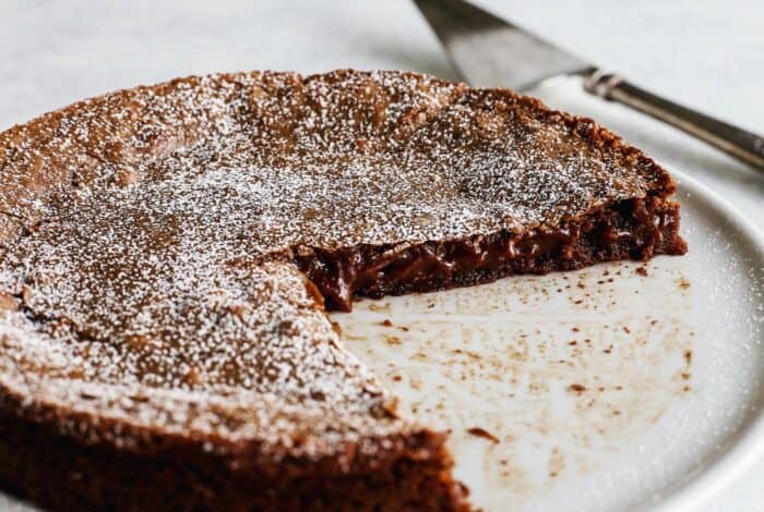 Torta svedese al cioccolato appiccicosa e appiccicosa su un piatto da torta con piedistallo bianco