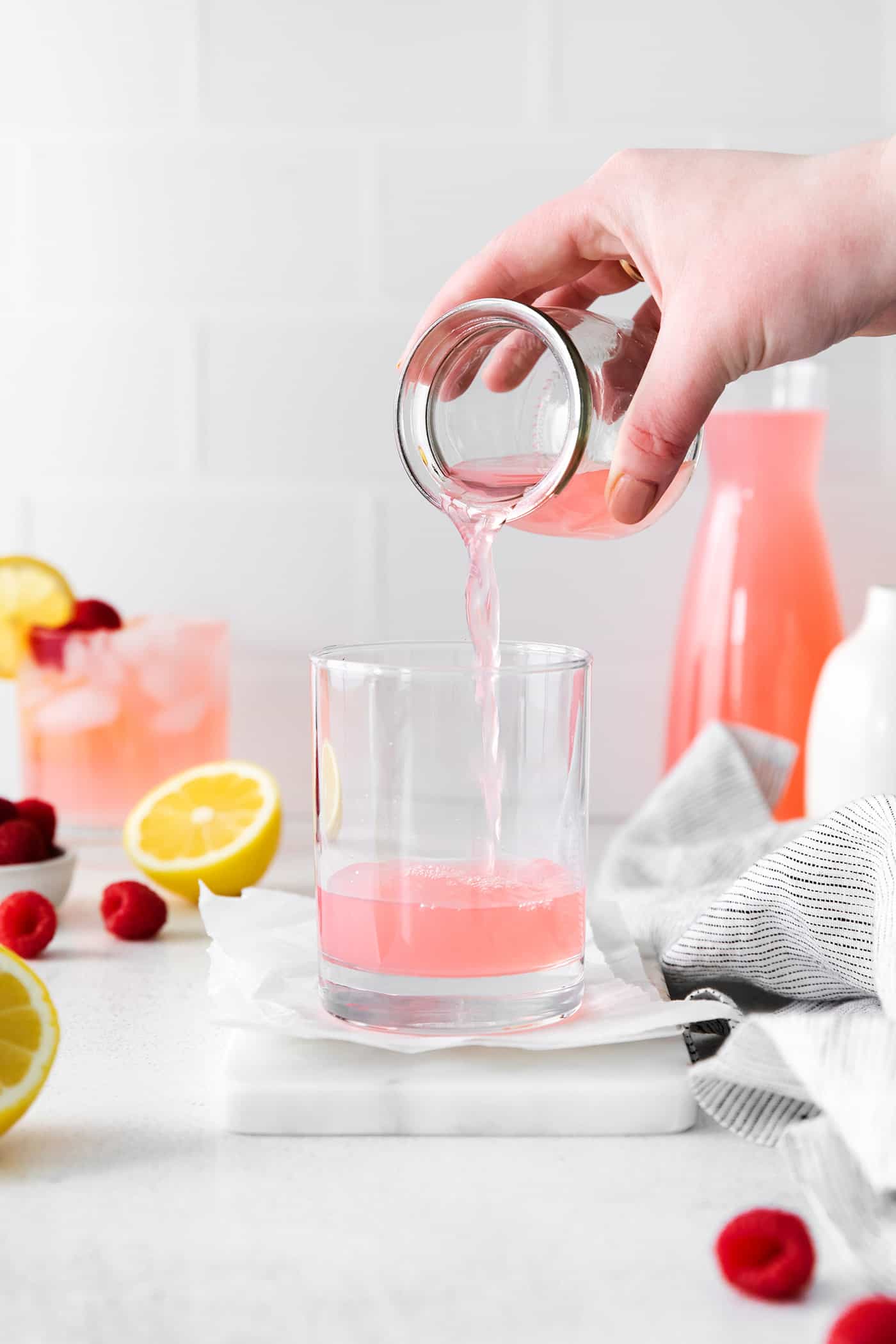 Pink lemonade being poured into a cocktail glass