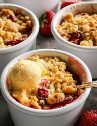 white ramekins with strawberry rhubarb crumble and vanilla ice cream