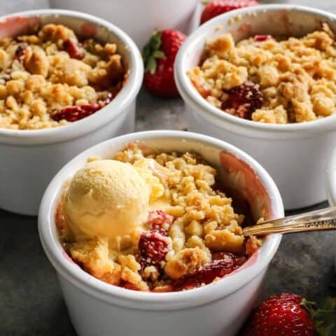 white ramekins with strawberry rhubarb crumble and vanilla ice cream