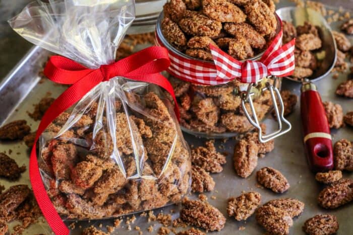 candied pecans in a small clear bar with a red ribbon and in a jar with red gingham ribbon
