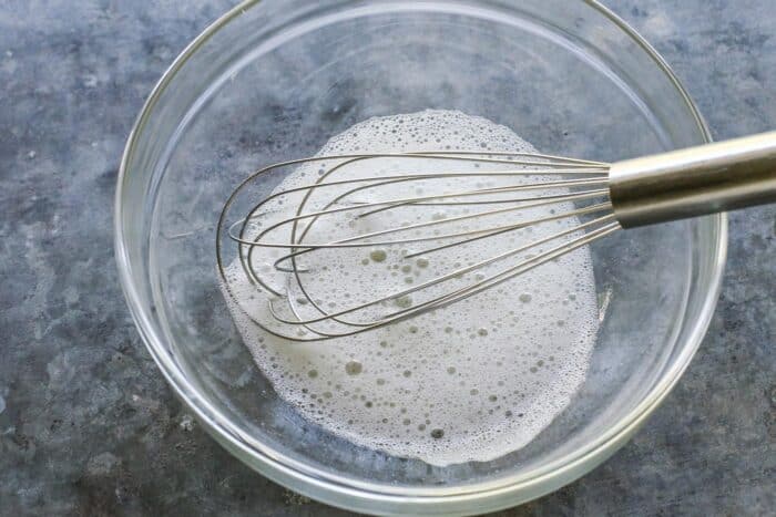 clear bowl with a whisk and whipped frothy egg white