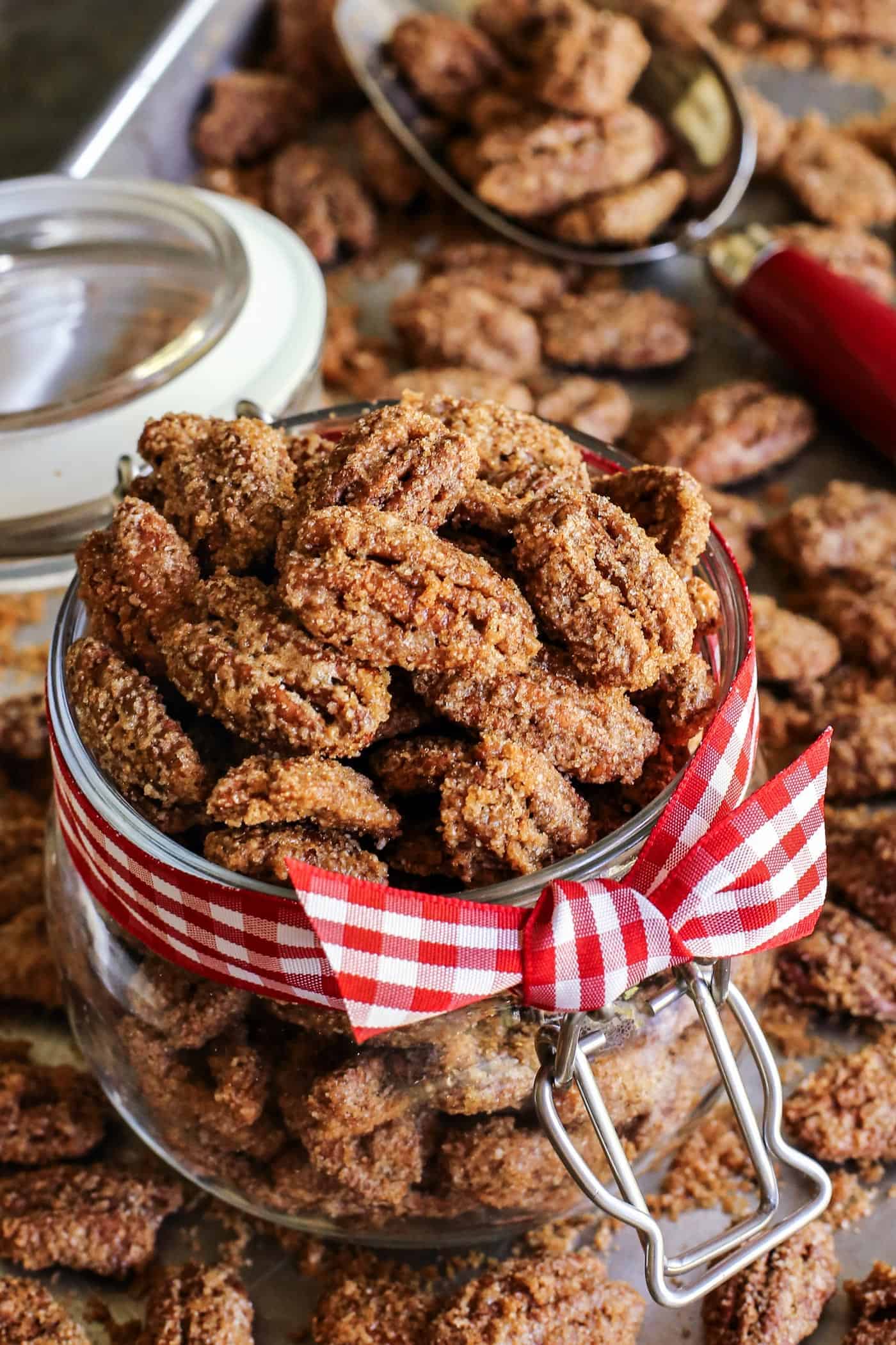 candied whole pecans in a jar with a red gingham ribbon tied around it