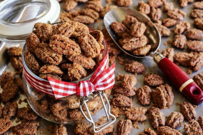 a pan of baked candied pecans, some of the pecans are in a jar