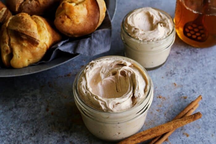 two jars of whipped cinnamon honey butter and a basket of popovers 