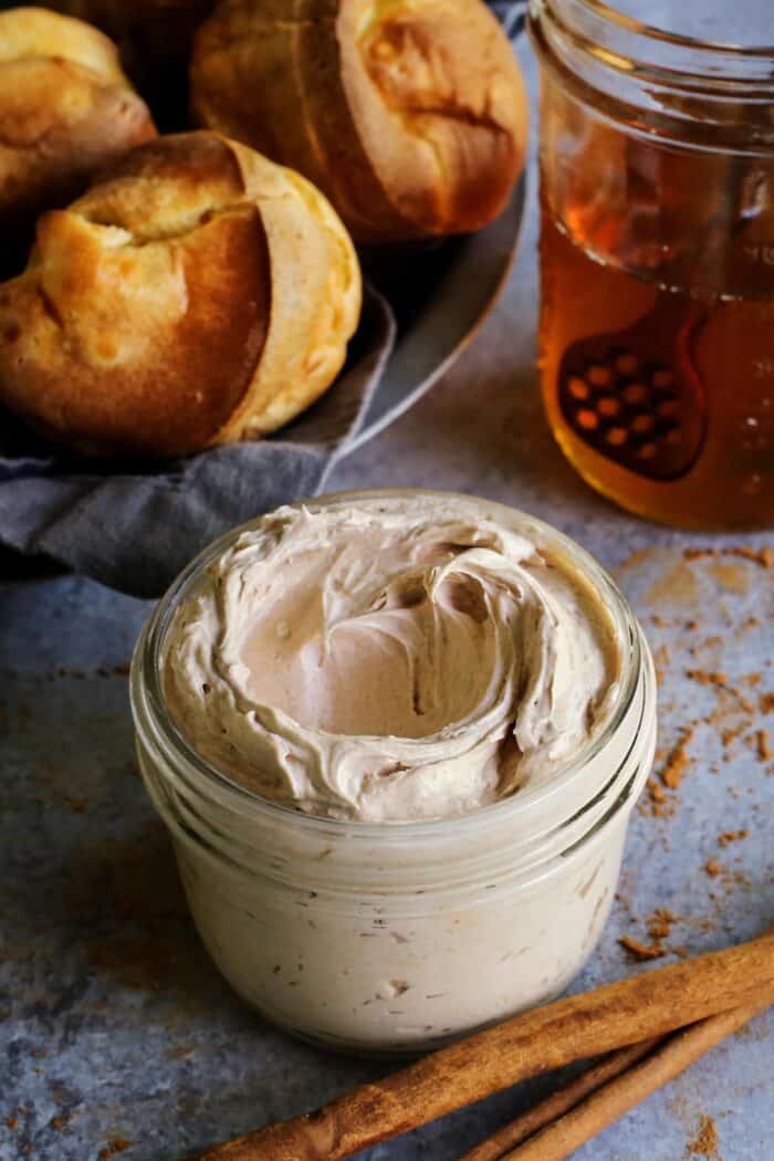 jar of whipped cinnamon honey butter, jar of honey, and basket of popovers