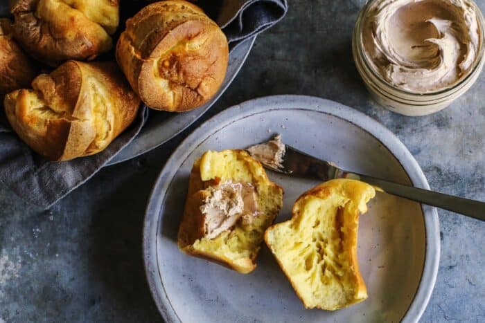 a popover split open and spread with cinnamon honey butter