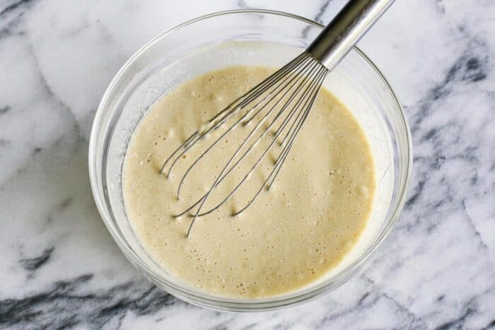 bowl of popovers batter with a whisk in it