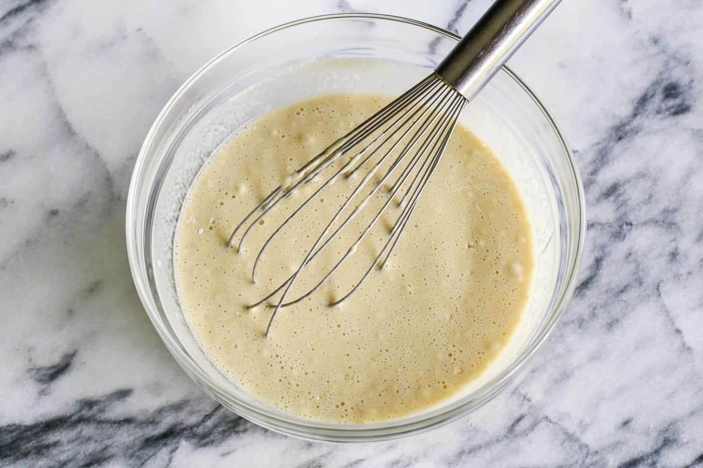 Bowl of popover batter with a whisk in it.
