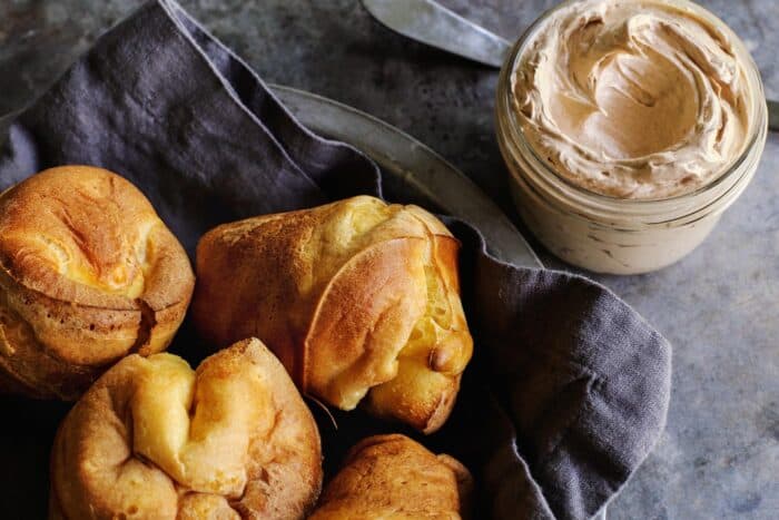 popovers in a basket and jar of cinnamon honey butter