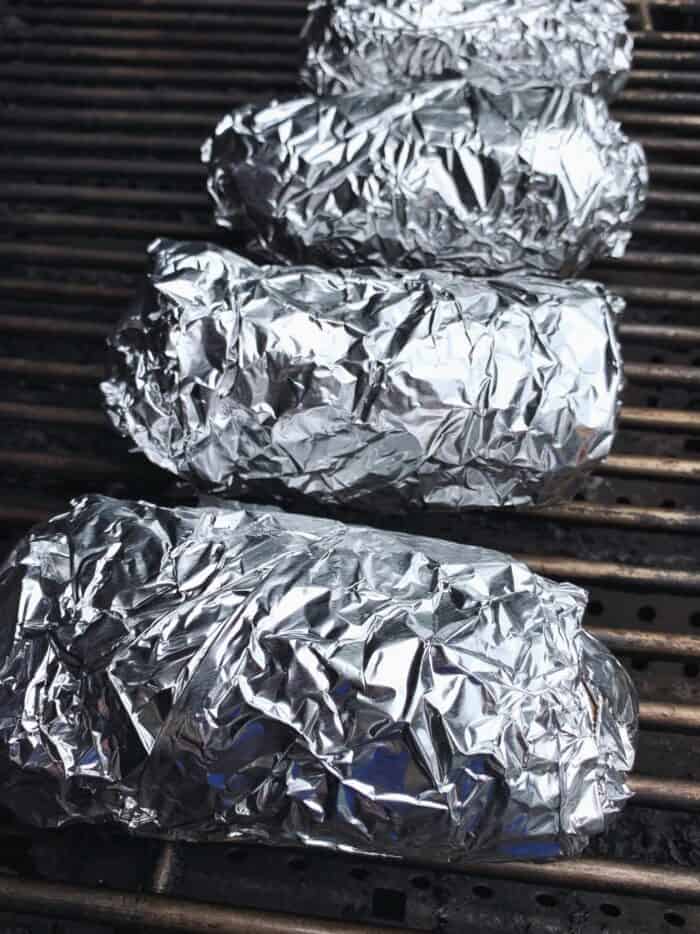 potatoes wrapped in foil on a grill