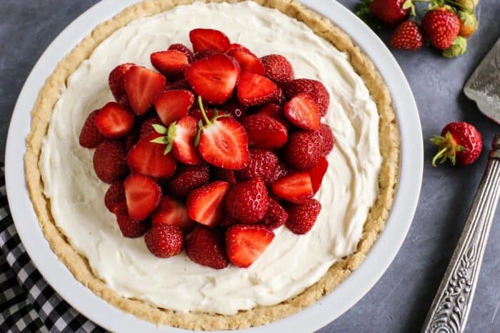 cream cheese pie in a white pan, topped with fresh strawberries