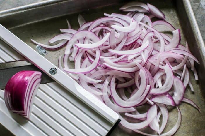 slicing a red onion with a mandoline