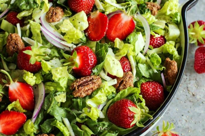 candied pecans on a salad of fresh greens with strawberries