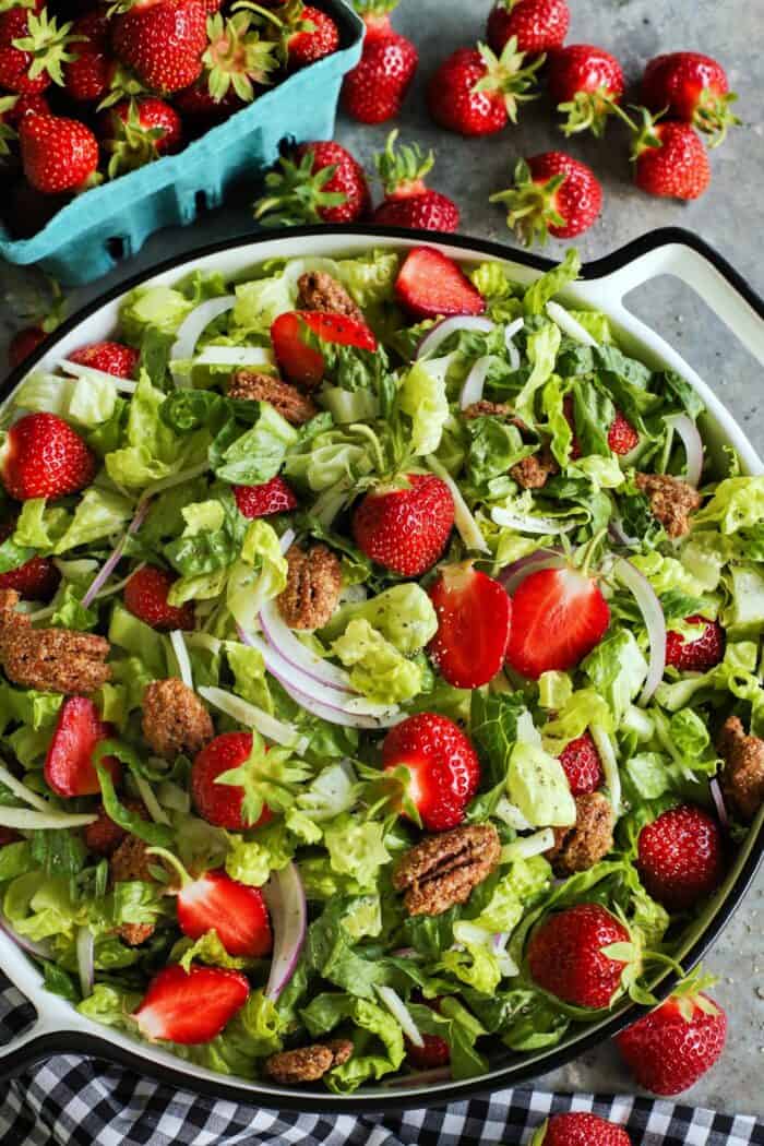 a box of ripe strawberries and strawberry salad in a large bowl